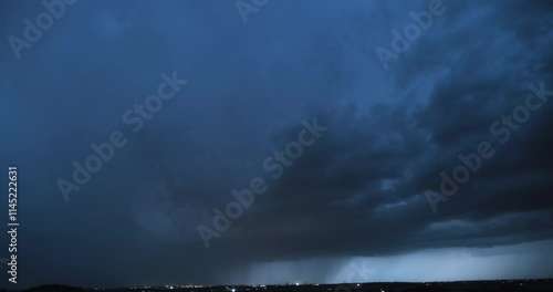 Timelapse of a heavy thunderstorm with visible curtain of falling rain and lightning strikes flashing fast as the storm cloud is slowly getting closer to the camera and more intense