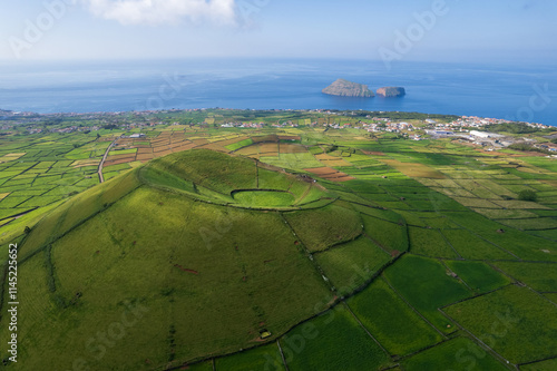 Aerial view of Terceira islans in Azores, Portugal. Volcanic landscape.  Drone shot of ancient Pico Dona Joana volcano and  cabras islet. Green fields in rural environment.