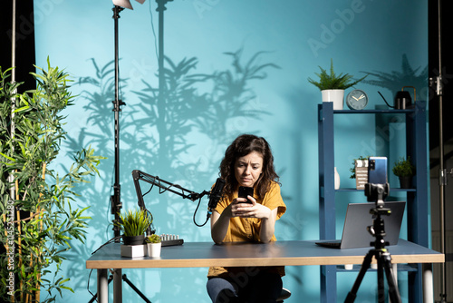 Photos Unhappy woman frowning after receiving upsetting text messages while filming video for online channel