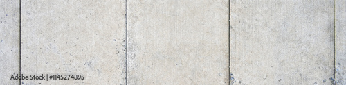 New cement sidewalk weathered and worn with aggregate rocks showing through the erosion, as a gray textured background

