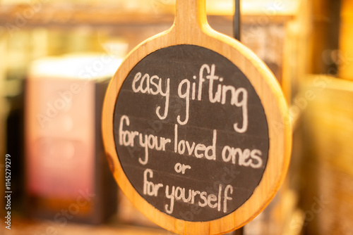 A small round chalkboard with a wooden frame and handle. Written in white chalk on the message board is easy gifting for your loved ones or for yourself. The sign is posted in a store for customers. photo