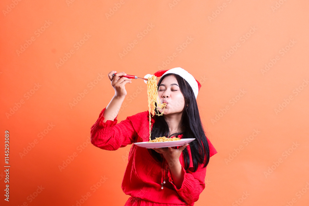 portrait of a woman wearing christmas dress, santa hat, slurping noodles with closed eyes, hand holding fork filled with noodles in front of head and white plate filled with noodles, isolated portrait of a woman wearing christmas dress, santa hat, slurping noodles with closed eyes, hand holding fork filled with noodles in front of head and white plate filled with noodles, isolated