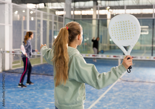 Active teen girl playing padel on the tennis court photo