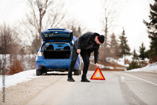Photos man putting triangle caution sign on road near broken car