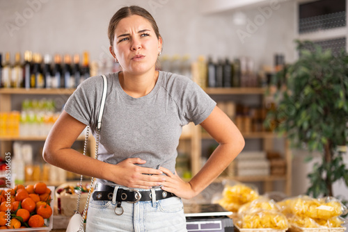 Φωτογραφία Young woman fidgeting by the stomach in the store