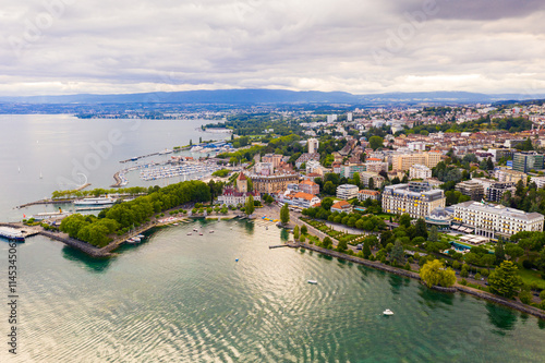 Picturesque view of Lausanne city on shore of Lake Geneva on background of mountains on summer day, Switzerland