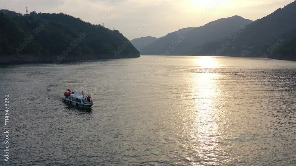 Stunning aerial view of a boat sailing during a dramatic sunset over a tranquil mountain river Stunning aerial view of a boat sailing during a dramatic sunset over a tranquil mountain river