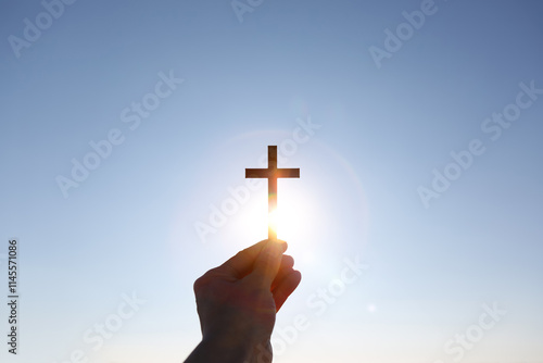 Canvas Print Lifting the cross of Jesus Christ toward the bright sunrise sunlight
