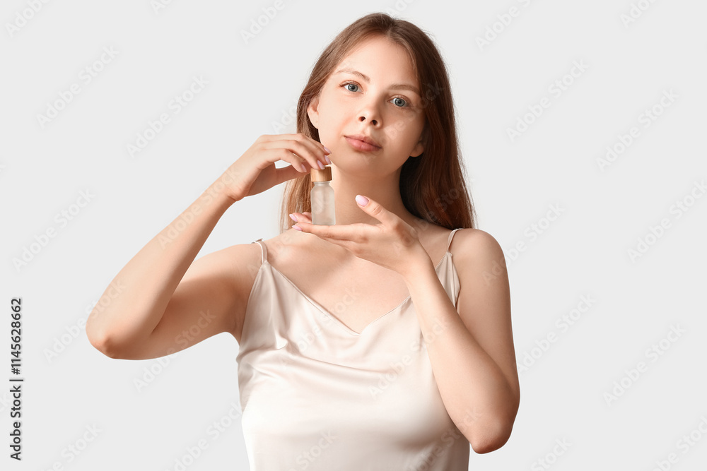 Pretty young woman with cosmetic oil on light background Pretty young woman with cosmetic oil on light background