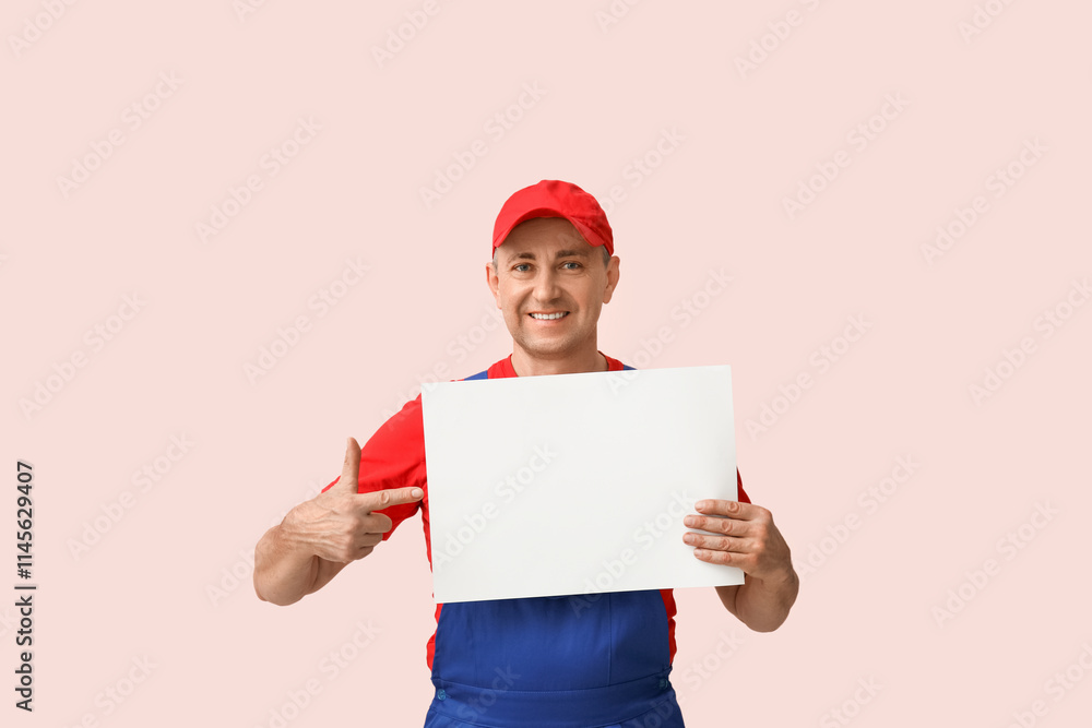 Portrait of male mechanic pointing at blank poster on pink background Portrait of male mechanic pointing at blank poster on pink background