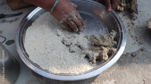 Indian woman cooking bajre ki roti on a traditional clay chulha, showcasing rural lifestyle and traditional cooking methods. photo