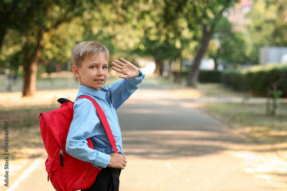 Cute little boy with backpack waving hand outdoors Cute little boy with backpack waving hand outdoors