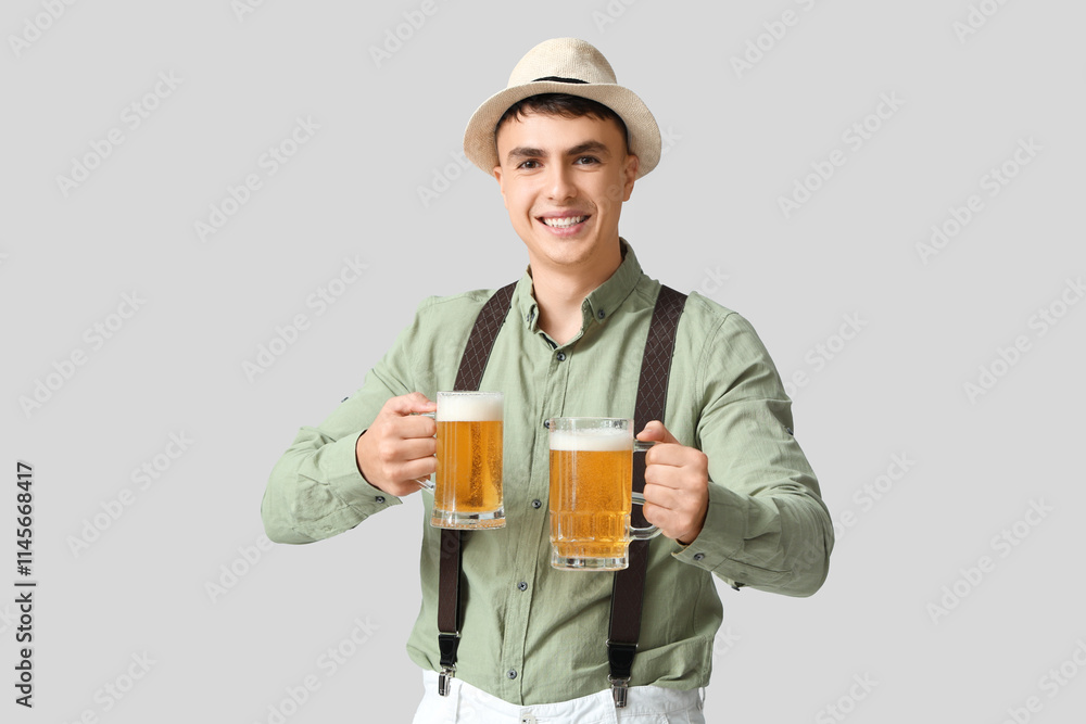 Young man in traditional German clothes with mugs of beer on white background. Octoberfest concept Young man in traditional German clothes with mugs of beer on white background. Octoberfest concept