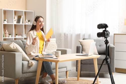 Young woman in headphones with notebook recording podcast at home