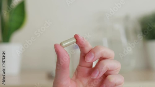 Close-up Woman holding gray capsule tablet