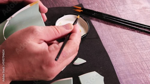 Kintsugi concept. Person repairing a cup with gold.