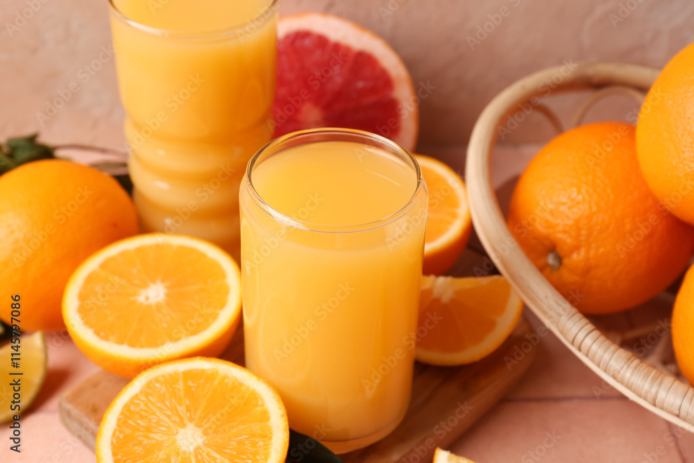 Wooden board with glasses of tasty juice and oranges on beige tile table