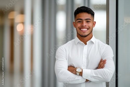 Confident young man poses in a modern office setting with a bright smile in a well-lit environment