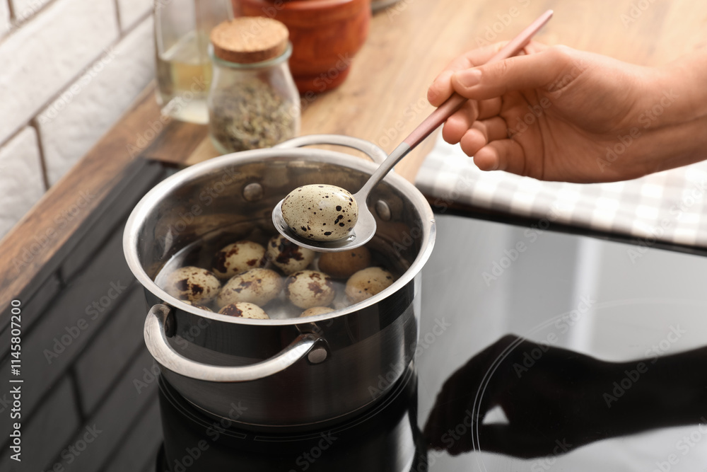 Woman holding spoon with boiled quail egg above cooking pot on electric stove Woman holding spoon with boiled quail egg above cooking pot on electric stove