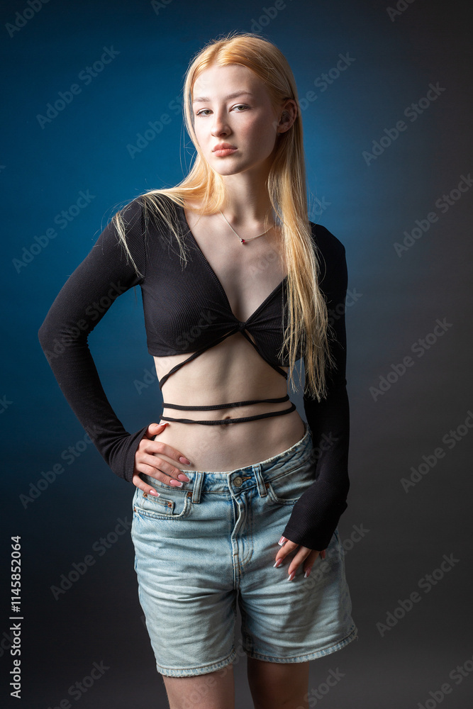 Portrait of a blonde woman with freckles in a sexy top and denim shorts in a studio. Portrait of a blonde woman with freckles in a sexy top and denim shorts in a studio.