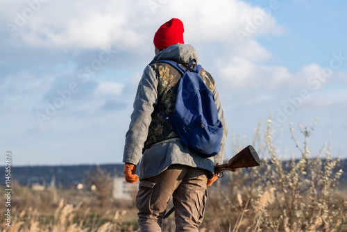 Mature hunter man holding a shotgun and walking through a field photo