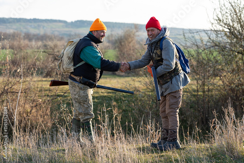 Mature hunter man holding a shotgun and walking through a field photo