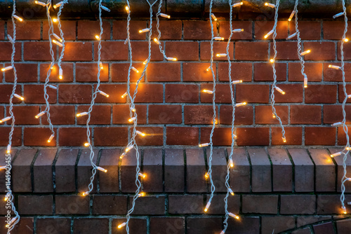 New Year's street garland with glowing bulbs. Spots of light are visible on the brick wall. Background. Texture.