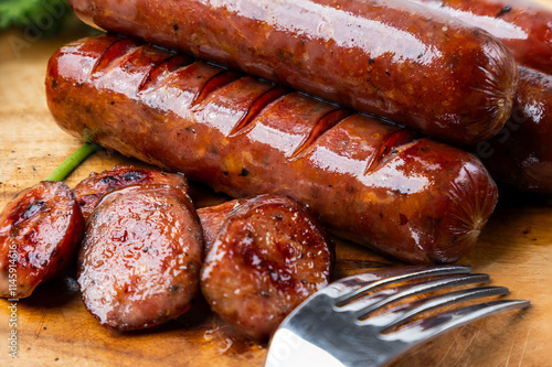 A stack of seared smoked sausages with glistening, crispy edges on a wooden cutting board, their caramelized exteriors revealing a perfect balance of smoky and savory flavors