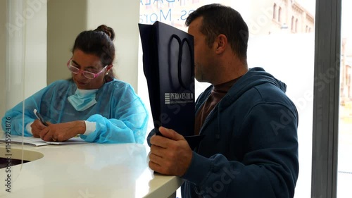 Satisfied male patient holds a gift bag while waiting at dental reception photo