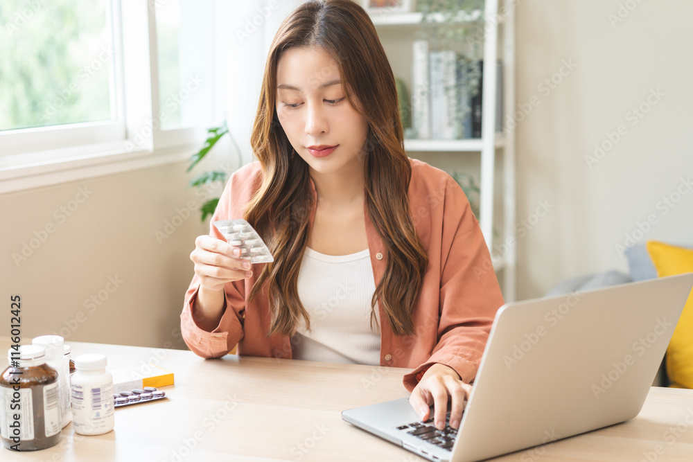 Wellness and dieting asian young woman, girl working from home using computer, typing or searching prescription on medicine label about vitamins information online, holding capsules of food supplement Wellness and dieting asian young woman, girl working from home using computer, typing or searching prescription on medicine label about vitamins information online, holding capsules of food supplement
