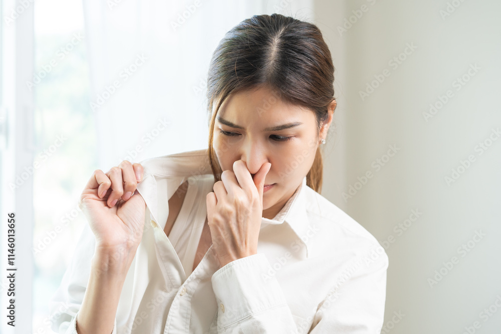 Bad smell nose concept asian young housewife woman having smelling clothes her shirt collar, sniff smelly dirty stinky musty, look disgusting from clothes after washed, laundry out of machine at home. Bad smell nose concept asian young housewife woman having smelling clothes her shirt collar, sniff smelly dirty stinky musty, look disgusting from clothes after washed, laundry out of machine at home.
