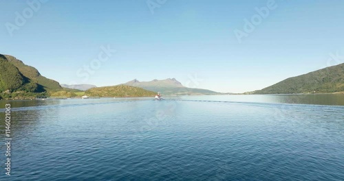 Gratangen or Rivtták, boat navigating in fjord, summer season, Troms, Norway. Aerial forward at low altitude, copy space photo