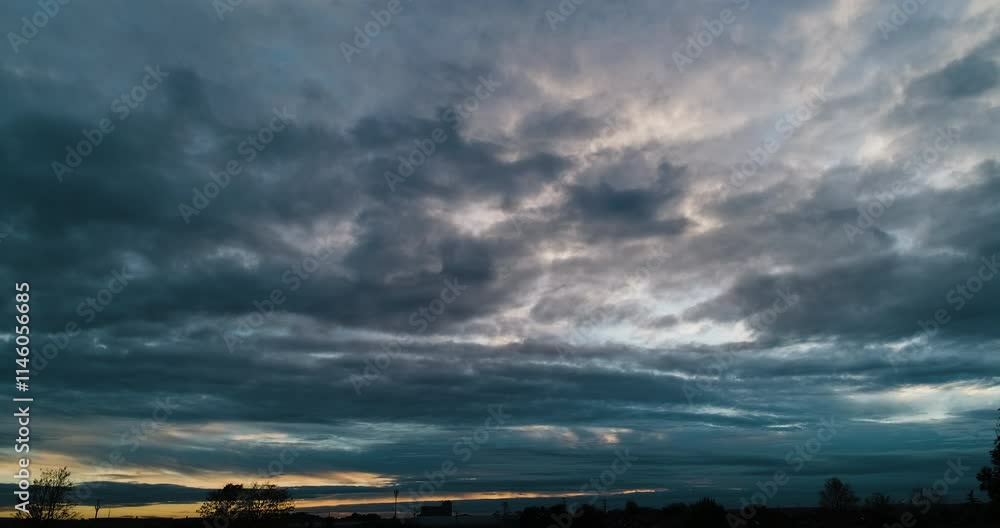 Timelapse of the overcast sky with dark storm clouds moving toward camera and orange glow of sunset on the horizon Timelapse of the overcast sky with dark storm clouds moving toward camera and orange glow of sunset on the horizon