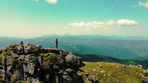 Canvas Print Woman standing on rocky mountain peak overlooking vast landscapes