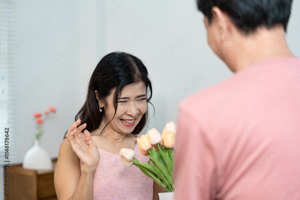 Joyful Senior Couple Celebrating Valentine's Day with Flowers and Smiles in a Cozy Home Setting Joyful Senior Couple Celebrating Valentine's Day with Flowers and Smiles in a Cozy Home Setting