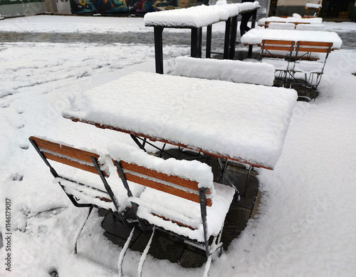 white snow on tables and chairs. Cafe terrace of cafe. Maribor, Slovenia. Winter