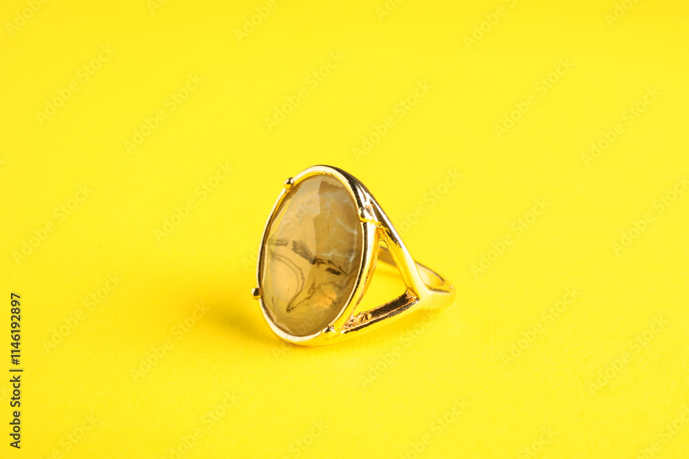 Beautiful bijouterie. Elegant ring on yellow background Beautiful bijouterie. Elegant ring on yellow background