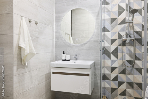 A modern bathroom with stylish geometric tiles, a beautiful circular mirror, functional and elegant