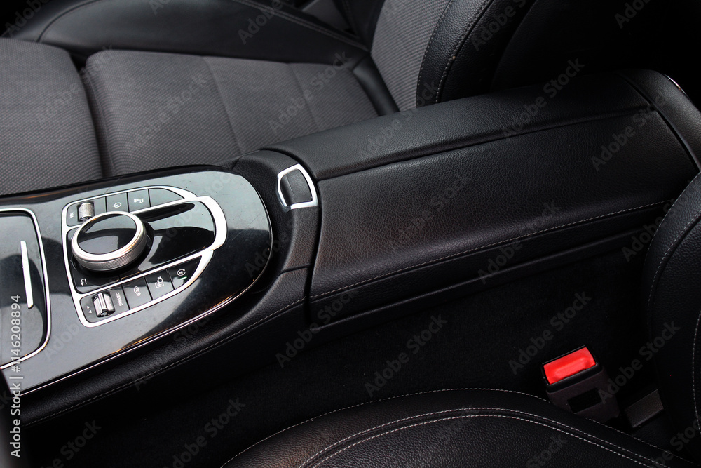 Armrest in driver's car is upholstered in eco-leather. Armrest central console with cup holders. Beautiful leather car interior design. Luxury leather seats in car. Black leather seat covers in car