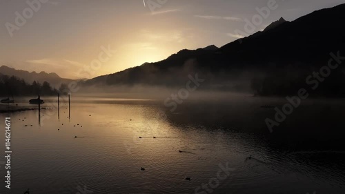 sunrise over a misty Walensee lake with silhouettes of mountains in Switzerland photo