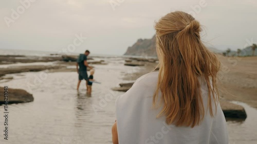 Redhead mother looking to caring father walking with son kid enjoy summer travel vacation at beach