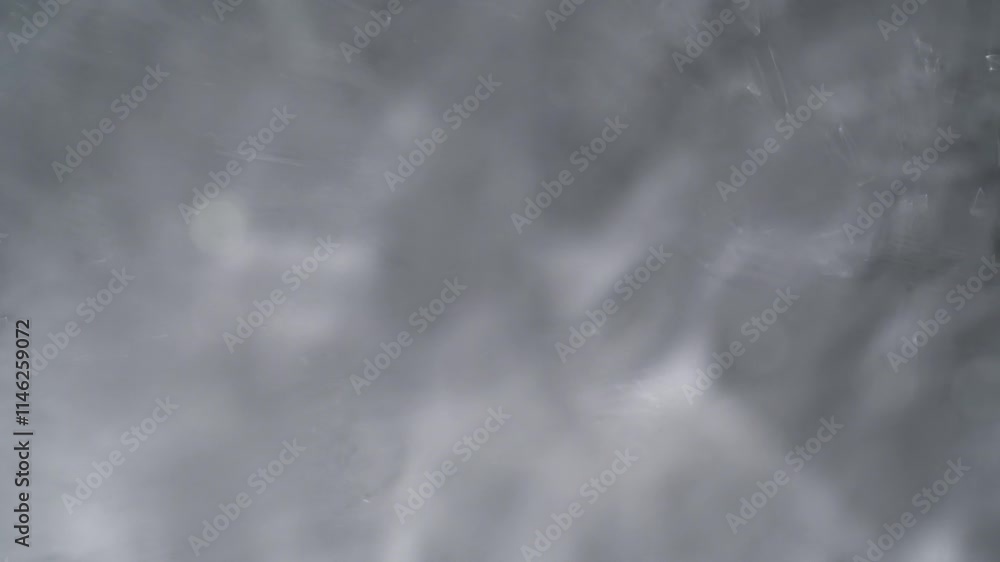 Transparent clear water texture with wavy surface rippling and flowing under rays of light on grey background. Abstract water background template. Transparent clear water texture with wavy surface rippling and flowing under rays of light on grey background. Abstract water background template.