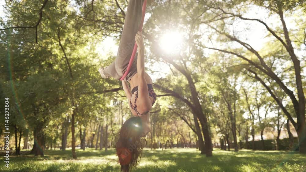 Girl hanging upside down on a gymnastics ring, showcasing strength and agility Girl hanging upside down on a gymnastics ring, showcasing strength and agility
