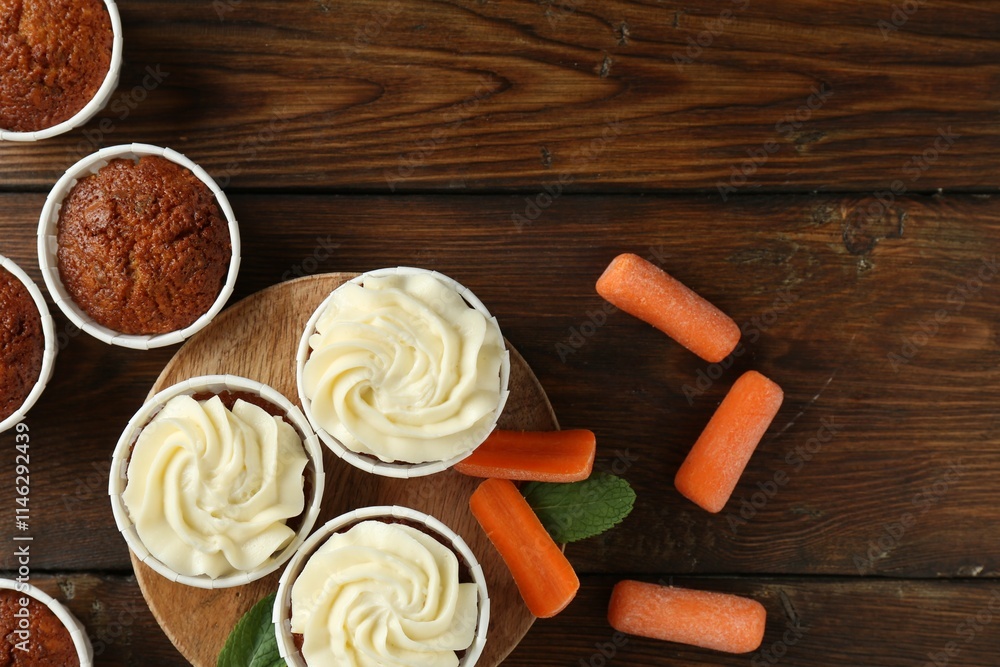 Tasty carrot muffins and fresh vegetables on wooden table, flat lay. Space for text Tasty carrot muffins and fresh vegetables on wooden table, flat lay. Space for text