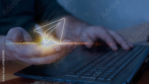 Digital communication concept with glowing paper plane icon in a hand, symbolizing online messaging, file sharing, and innovative technological connection through modern devices like laptops and smart photo