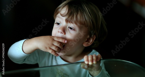 Toddler boy grabbing food from the edge of table. Child grabs toast photo