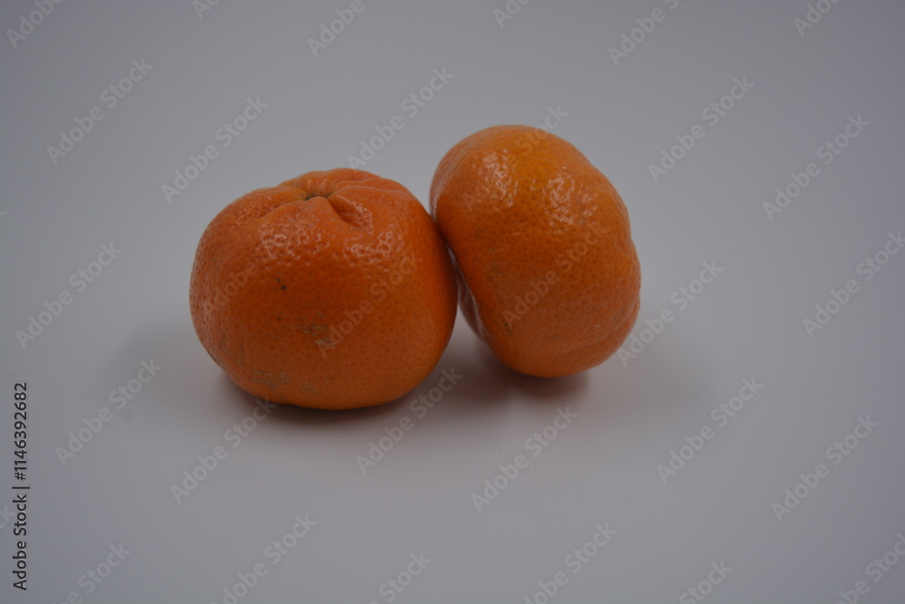 Healthy, healthy food, fresh fruit. Beautiful two whole ripe orange tangerines are located on a white plastic background. Healthy, healthy food, fresh fruit. Beautiful two whole ripe orange tangerines are located on a white plastic background.