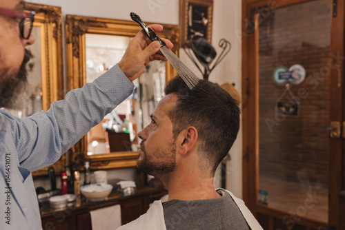 A man is getting his hair cut by another man in a barbershop