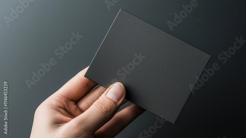 A hand holding a blank card against a dark backdrop.