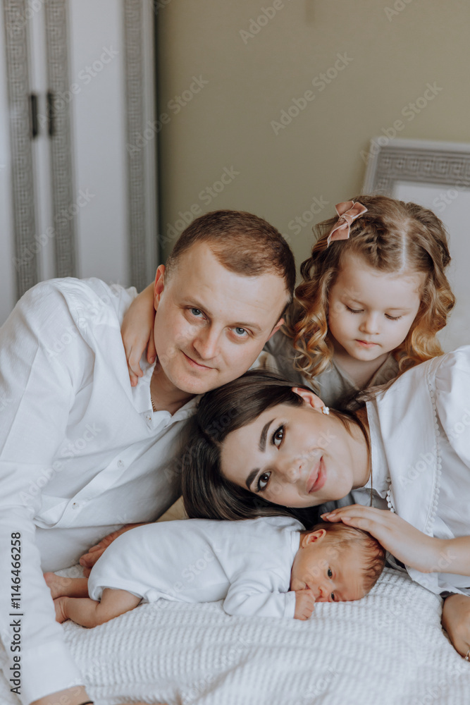 Fototapeta premium A family of four, including a couple and their two children, are posing for a picture with a newborn baby. Scene is warm and loving, as the family is embracing